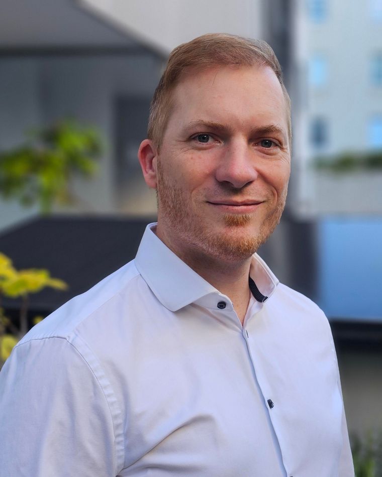 Max Blöchle, Gründer von 42 Future Works, im Freien vor einer Stadtfassade mit Photovoltaikmodulen